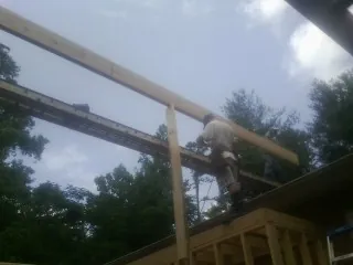 Carpenter setting a ridge beam over a new addition frame — Ice Dam Removal by Roofing Brothers in Saegertown