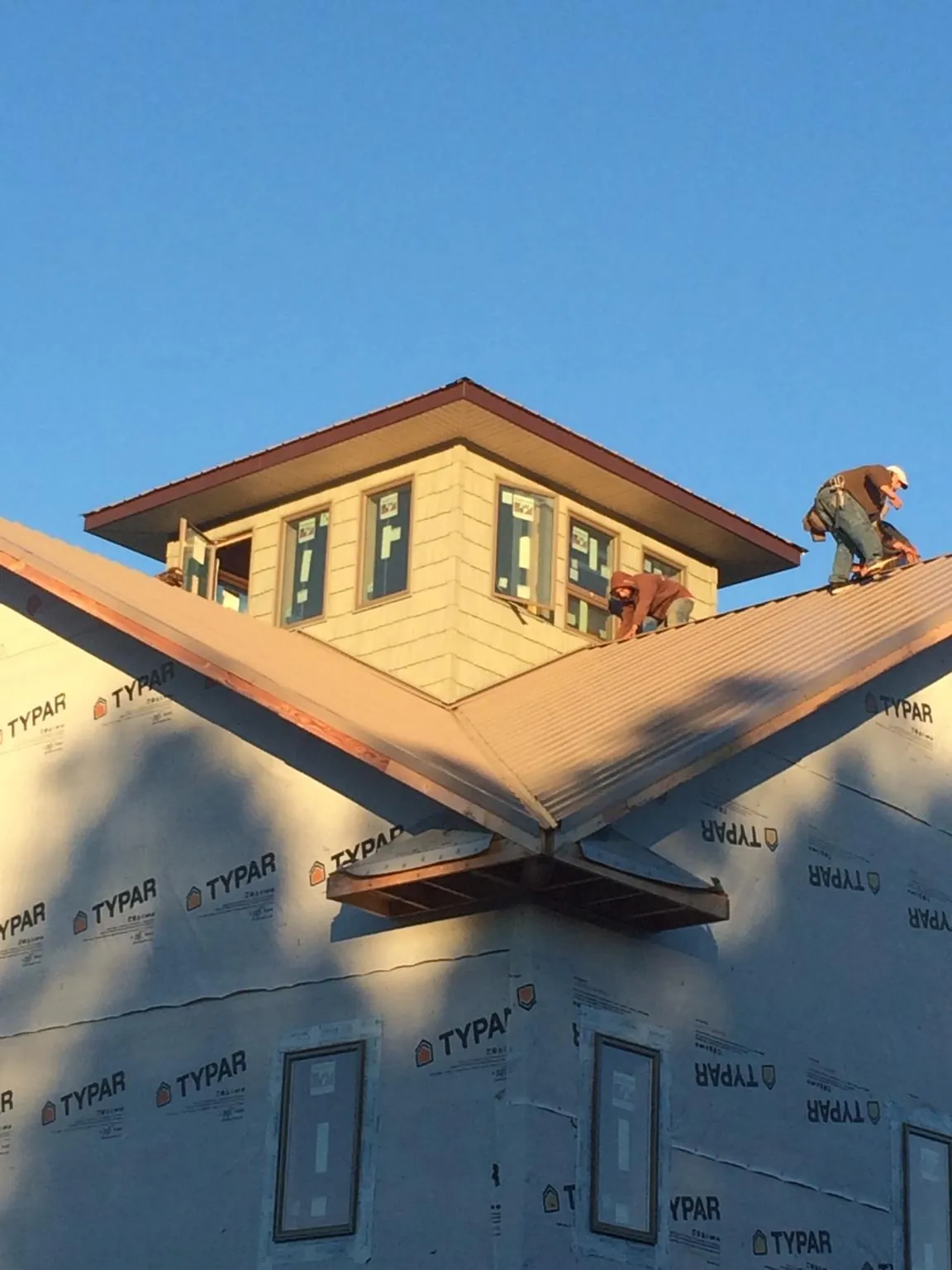 Roofers working around a rooftop cupola on a new metal roof at sunset — Roof Waterproofing in Saegertown by Roofing Brothers